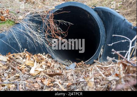 HDPE-Drainage unter einer Straßeneinfahrt. Das Rohr dient zur Förderung von Regenwasser zwischen Gräben. Stockfoto