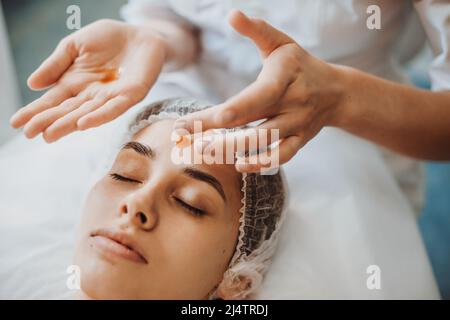 Kaukasische Frau mit Gesichtsbehandlung im Spa-Salon mit Massageöl. Verjüngungskur. Arztzand. Medizinische Behandlung. Stockfoto