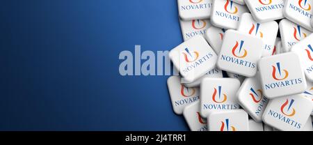 Logos des Schweizer Pharmaunternehmens Novartis auf einem Haufen auf einem Tisch. Speicherplatz kopieren. Webbanner-Format. Stockfoto
