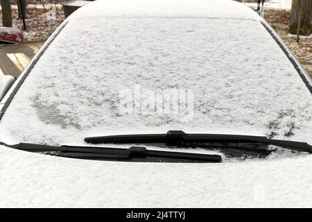 Nahaufnahme von Graupel Schneepellets auf einem Windschutz eines Fahrzeugs Stockfoto