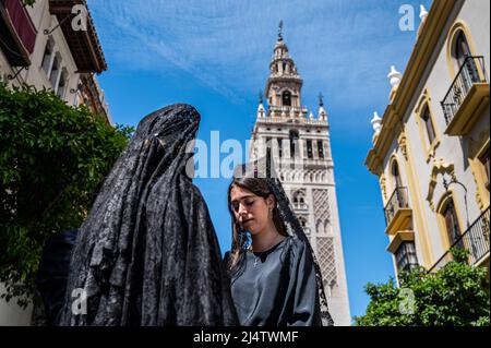 Sevilla, Spanien. 14. April 2022. Frauen, die mit traditionellen „Mantilla“ (Haarteil und Schleier) gekleidet sind, werden während der Feierlichkeiten der Karwoche in der Nähe der Kathedrale gesehen. Nach zwei Jahren der Reisebeschränkungen von Covid-19 und der Aufhebung der sozialen Aktivitäten in Spanien konnte das Unternehmen seine Aktivitäten zur Feier der Karwoche wieder aufnehmen. (Bild: © Miguel Candela/SOPA Images via ZUMA Press Wire) Stockfoto