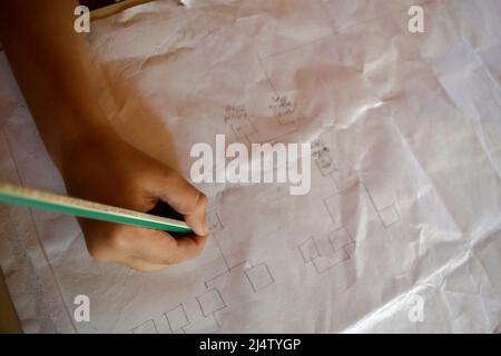 Nahaufnahme der Hand des Kindes, die ein Diagramm oder ein Flussdiagramm auf Papier zeichnet Stockfoto