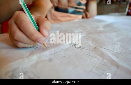 Nahaufnahme der Hand des Kindes, die ein Diagramm oder ein Flussdiagramm auf Papier zeichnet Stockfoto
