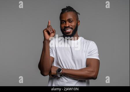 Fröhlicher Mann mit einem hochgedrehter Zeigefinger, der nach oben schaut Stockfoto