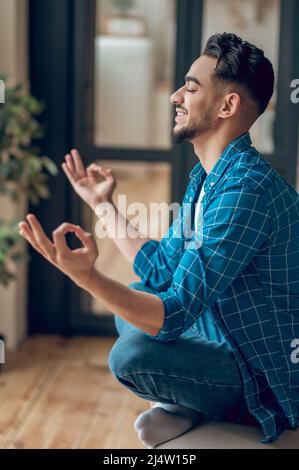 Positive junge Yogi sitzen in Lotushaltung mit Fingern in giana Mudra Stockfoto