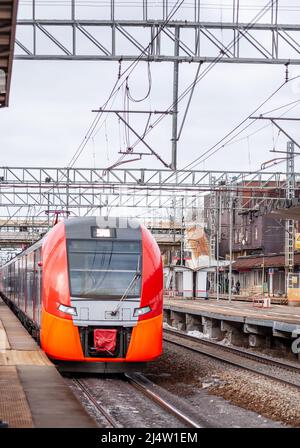 1. April 2022, Moskau Russland. Der moderne Hochgeschwindigkeitszug bewegt sich schnell entlang der Plattform. Die Leute warten auf den Zug am Bahnhof, öffentliche Verkehrsmittel Stockfoto