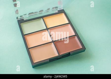 Schminkpalette mit bunten Concealern auf minzfarbenem Hintergrund. Selektiver Fokus. Stockfoto