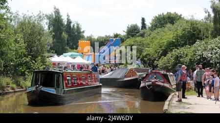 An einem sonnigen Wochenende im Juni 2017 fährt ein Kanalverleih durch den Ort des Middlewich Folk and Boat Festival auf dem Trent and Mersey Kanal Stockfoto