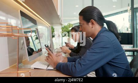Business People Group mit Smartphones mit Entspannung am Arbeitsplatz Schreibtisch im Büro hält mobile Geräte Kommunikationstechnologie Social Stockfoto