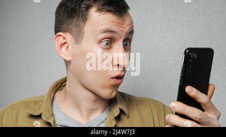 Der Mann nimmt die Brille ab, nachdem er die Nachrichten auf dem Mobiltelefon gelesen hat Stockfoto