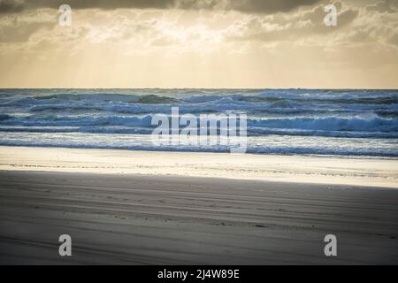 Am frühen Morgen am 75 Mile Beach, mit Lichtstrahlen, die durch die Wolken strömen, was zu einer surrealen Szene führt. Fraser Island, QLD, Australien. Stockfoto