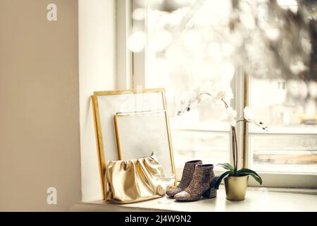 Home Mockup mit Rahmen aus der Nähe stehen auf Fensterbank mit goldenen Accessoires und Orchidee Winter Abendzeit im Zimmer mit Kronleuchter Stockfoto