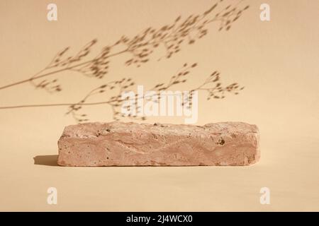 Stein Podium für die Förderung auf beigem Hintergrund. Natürlicher Sockel. Zwei Steinpodien mit Blumenschatten. Modellbau für Schönheitsprodukte. Szene Stockfoto
