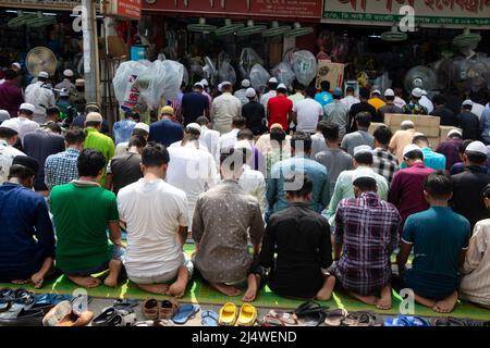 Non Exclusive: NARAYANGANJ, BANGLADESH - APR 15, 2022: Muslimische Anhänger knien mitten auf einer belebten Straßenkreuzung, um Jummah-Gebet auf einer Straße anzubieten Stockfoto