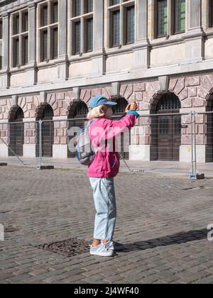 Antwerpen, Belgien, 17. April 2020, eine ältere Dame in Mütze fotografiert mit ihrem Smartphone das Rathaus auf dem Marktplatz in Antwerpen Stockfoto