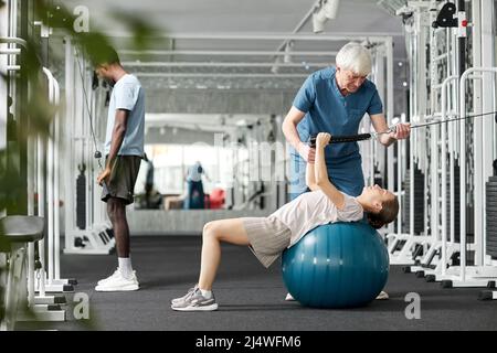 Porträt eines älteren Rehabilitationstherapeuten, der mit Patienten im Fitnessstudio in der Klinik arbeitet, Kopierraum Stockfoto