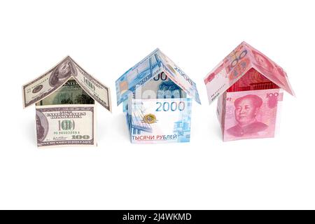 Häuser aus Dollar, Rubel und Yuan, isoliert auf weißem Hintergrund Stockfoto