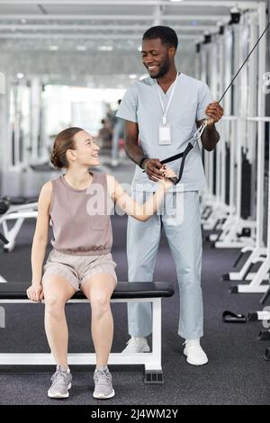 Porträt eines lächelnden medizinischen Therapeuten, der weiblichen Patienten in der Rehabilitationsklinik assistiert, Kopierraum Stockfoto