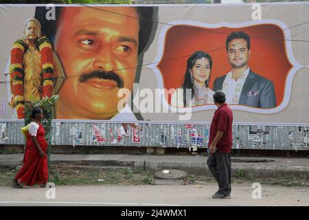 Zwei Menschen gehen an einer Wand vorbei, die mit einem Wahlkampfplakat in Trichy, Tamil Nadu, Indien, bedeckt ist Stockfoto