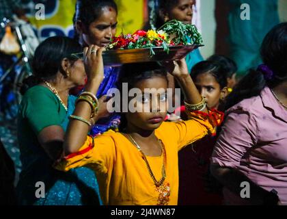 Junge Frau, die während eines religiösen Festivals in Trichy, Tamil Nadu, Indien, Opfergaben auf dem Kopf trägt Stockfoto