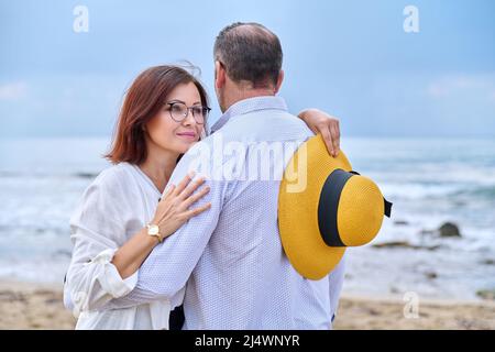 Portrait von glücklich umarmt mittleren Alters Paar, Meer Natur Himmel Wellen Hintergrund. Stockfoto