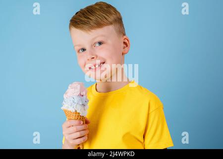 Positiver Junge mit Eis auf blauem Hintergrund. Gesundheitliche Vorteile Eis-Konzept Stockfoto