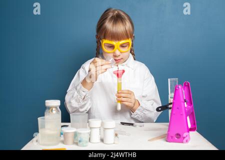 Neugieriger Student, der Flüssigkeit im Becher untersucht und wissenschaftliche Experimente im Labor durchführt Stockfoto