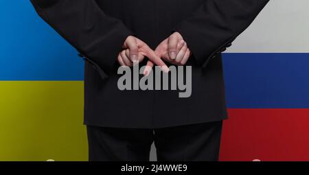 Mann mit gekreuzten Daumen auf ukrainischem und russischem Hintergrund Stockfoto