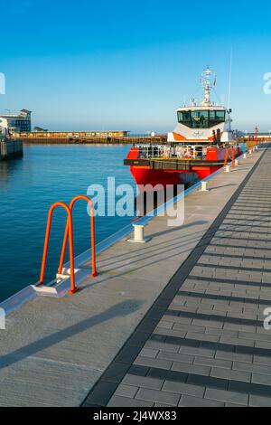 Helgoland, Deutschland - 02.27.2022: Roter Katamaran dockt in der Bucht im Hafen von Helgoland an. Sonniger Wintertag im deutschen Archipel im Norden Stockfoto