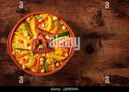 Fleisch- und Gemüsecouscous in einer Schüssel, typisches marokkanisches Essen, ein traditionelles festliches arabisches Gericht mit Kräutern und Gewürzen, von oben geschossen Stockfoto
