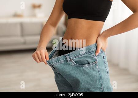 Unverkennbare Schwarze Dame Mit Bauchmuskeln, Die Übergroße Jeans In Der Halle Tragen Stockfoto