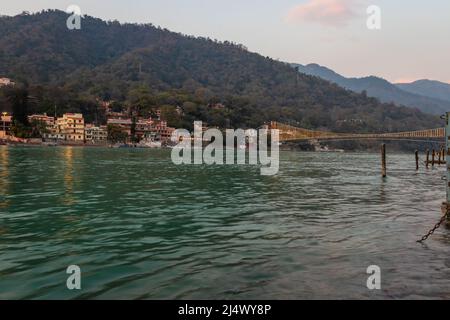 Stadtansicht mit eiserner Hängebrücke am Abend aus flachem Winkel Bild wird in rishikesh uttrakhand india am 15 2022. März aufgenommen. Stockfoto