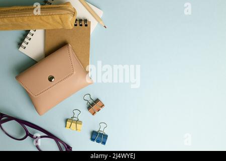 Notizblock, Clip, Bleistift, Tasche, Etui, Brille auf blauem Hintergrund. Flach liegend, Draufsicht, Kopierraum Stockfoto