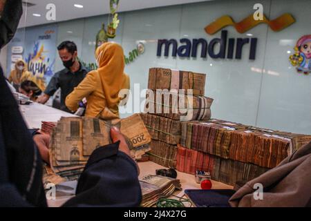 Bandung, Indonesien. 18. April 2022. Ein Kunde zählt Geld, das bei der Mandiri Mikro Business Unit Bandung Braga in Bandung hinterlegt wird. Die Bank Mandiri Region VI/Java 1 bereitet einen Bargeldbedarf von rund 6,6 Billionen IDR vor, um den steigenden Bargeldbedarf der Menschen in West-Java zu antizipieren. Der Wert umfasst 6,1 Billionen IDR für das Aufladen von 1207 Geldautomaten und 535 Milliarden Rp für die Kundenbedürfnisse in den nächsten 33 Tagen vom 7. April bis zum 9. Mai 2022, während des Ramadan und vor Eid al-Fitr 1443 H. Credit: SOPA Images Limited/Alamy Live News Stockfoto