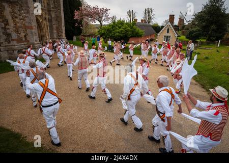 Ostermontag Morris Dancing Thaxted Essex, Großbritannien. 18. April 2022. Im späten Frühling bei warmem Wetter spielen Thaxted Morris-Tänzer in Rot und Weiß mit Devils Dyke Morris-Tänzern in Braun und Weiß aus dem Süden Cambridgshire traditionelle dMorris-Tänze im Thaxted Church Yard mit Thaxted Alms Houses und John Webbs Windmühle im Hintergrund. Kredit: BRIAN HARRIS/Alamy Live Nachrichten Stockfoto