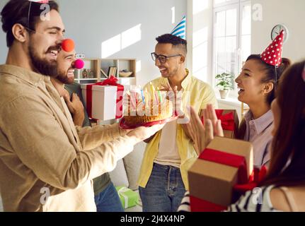 Lächelnde junge Leute grüßen einen Freund mit einem guten Geburtstag Stockfoto