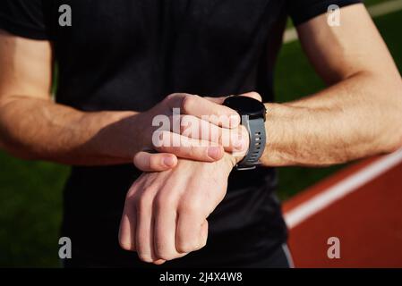 Nach den Übungen am Stadionständer überprüft der Mann die Uhr Stockfoto