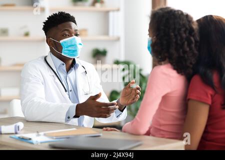 Kranke Tochter und Mutter besuchen Kinderarzt, trägt Gesichtsmasken Stockfoto