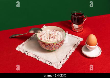 Serviert Frühstückstisch. Food Pop Art Fotografie. Teekocher, Grapefruit und Haferbrei auf roter Tischdecke auf grünem Hintergrund. Vintage-Retro-Style Stockfoto