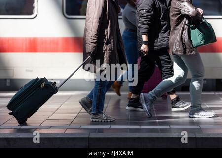 18. April 2022, Hessen, Frankfurt/Main: Reisende mit Gepäck laufen am Frankfurter Hauptbahnhof entlang eines Zuges. An besonders stark frequentierten Hauptbahnhöfen stehen zusätzliche Mitarbeiter am Osterwochenende und am Ostermontag zur Verfügung, um den Gästen beim Umsteigen und beim Ansteigen zu helfen. Foto: Hannes Albert/dpa Stockfoto