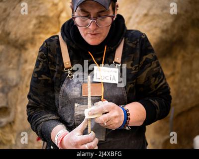 Die Bildhauerin, die auf der Straße an Stein arbeitet, hat ein Werkzeug und eine Brille Stockfoto