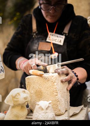 Konzentrieren Sie sich auf die Kunsthandwerkerin, die in MIERA, ITALIEN, einen Block aus lokalem Stein bastelt Stockfoto