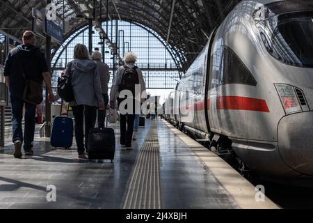 18. April 2022, Hessen, Frankfurt/Main: Reisende mit Gepäck laufen am Frankfurter Hauptbahnhof entlang eines Zuges. An besonders stark frequentierten Hauptbahnhöfen stehen zusätzliche Mitarbeiter am Osterwochenende und am Ostermontag zur Verfügung, um den Gästen beim Umsteigen und beim Ansteigen zu helfen. Foto: Hannes Albert/dpa Stockfoto