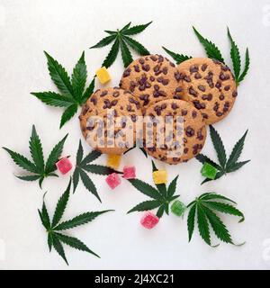 Amerikanische Cookies mit Cannabisextrakt. Süßigkeiten mit CBD-Öl. Marihuana Blätter auf weißem Hintergrund. Draufsicht, flach liegend. Stockfoto