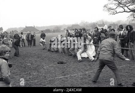 1980s, histrozial, Zuschauer beobachten lokale Männer, die an einem Tauziehen auf einem Sportplatz im Dorf, England, Großbritannien, teilnehmen. Mit einem uralten Hystroy ist das Tauziehen ein Test der Stärke zwischen zwei Teams, die an einem Seil in die entgegengesetzte Richtung ziehen, und wird oft in Dorfereignissen und Feten miteinbezogen und ist in vielen Ländern beliebt. Stockfoto