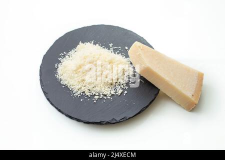 Geriebener Parmesan auf einer schwarzen Steinplatte, isoliert auf weißem Hintergrund. Platz für Text kopieren Stockfoto