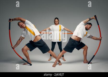 Menschen stehen zusammen und üben Stöcke. Karate-Meister posieren mit Stöcken im Studio zusammen. Stockfoto