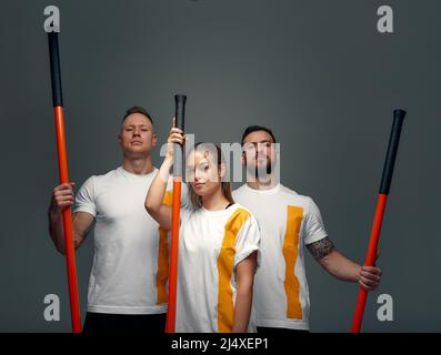 Menschen stehen zusammen und üben Stöcke. Karate-Meister posieren mit Stöcken im Studio zusammen Stockfoto