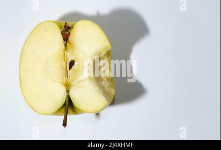 Apfel auf weißem Hintergrund gebissen. Einen halben Apfel roh. Frischer grüner Apfel mit einem Schatten. Stockfoto