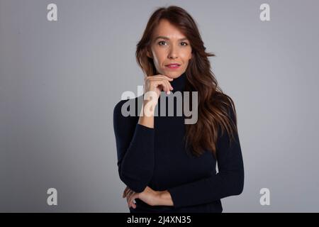 Studioporträt einer attraktiven langhaarigen Frau, die auf einem isolierten grauen Hintergrund steht. Speicherplatz kopieren. Stockfoto